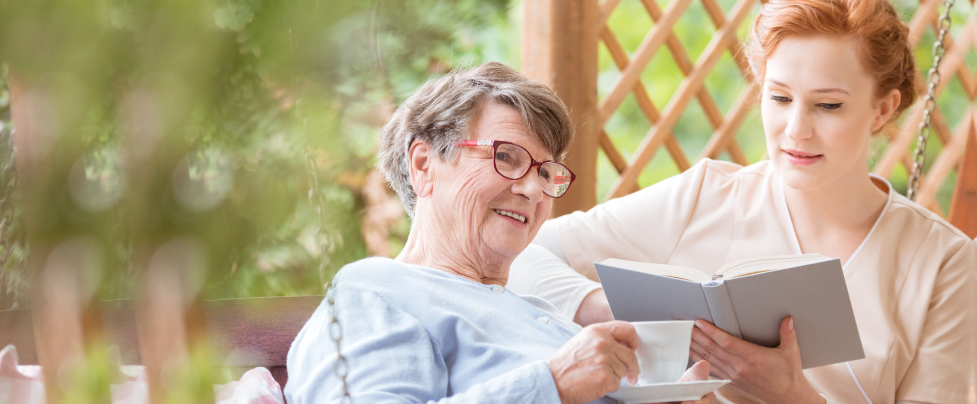 caregiver reading a book for a senior woman